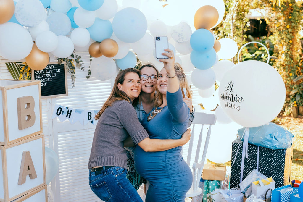 Female friends taking selfie with pregnant woman at a baby shower
