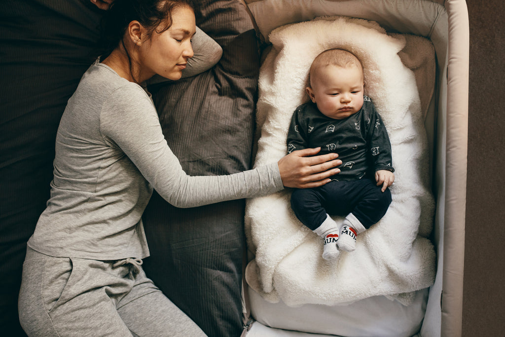 Baby boy in one of the best bassinets lying next to his sleeping mother